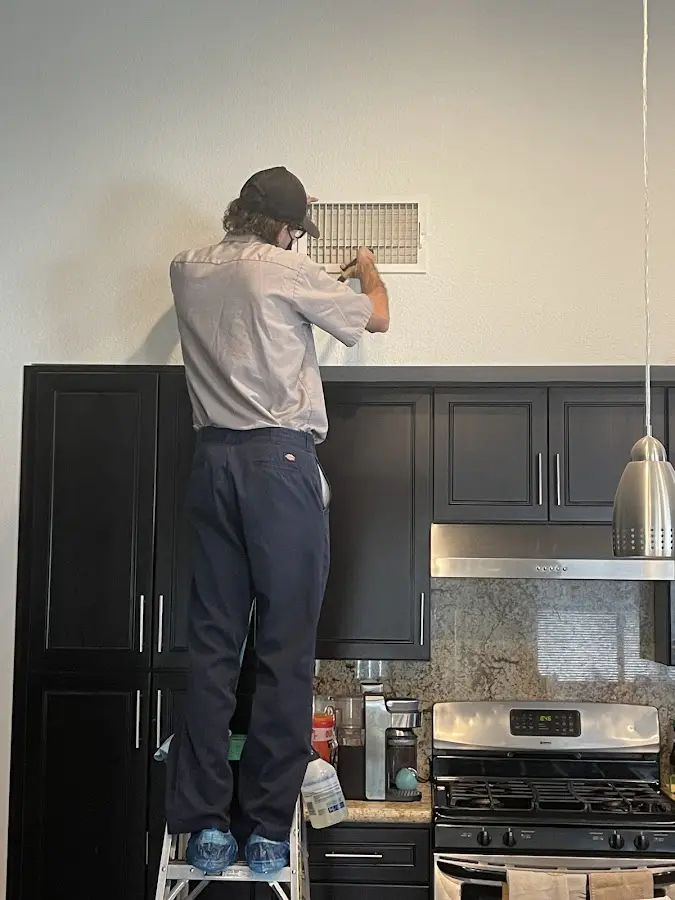 Technician inspecting an air vent during HVAC service in Crosspointe